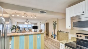 Una cocina con una isla central, electrodomésticos de acero inoxidable y vistas al área de estar.