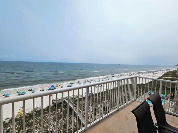 A balcony with a view of a beach, a pool, and a lifeguard tower. - Sandy Key 828: 3 BR / 2 BA Gulf Front Condo in Perdido Key, FL Sleeps 8 (Pensacola)