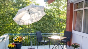 A balcony with a table, chairs, a potted plant, and an umbrella. - Flair Hotel zur Therme (Erwitte)