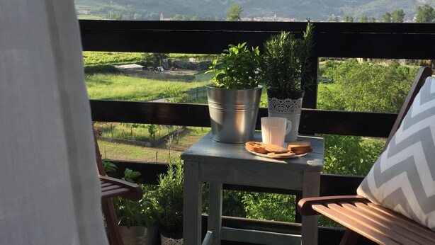 Un balcón con una mesa, una silla y vistas a las montañas.