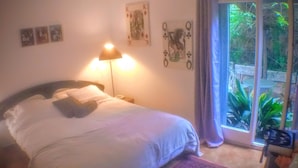 Un dormitorio con cama, mesita de noche, lámpara y ventana con cortinas.