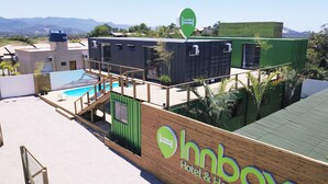 A modern hotel with a pool, wooden deck, and a sign for Innbox Hotel & Hostel. - Innbox - Praia Do Rosa - Hostel (Imbituba)