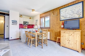 Una cocina acogedora con una mesa de comedor, sillas y un mueble de madera con un televisor.