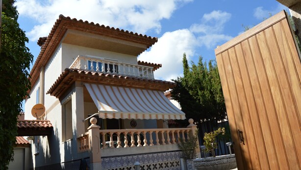 A two-story building with a tiled roof and a balcony with a white railing.