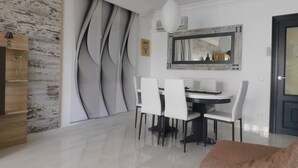 A dining area with a white table and chairs, a large mirror, and a wooden cabinet.