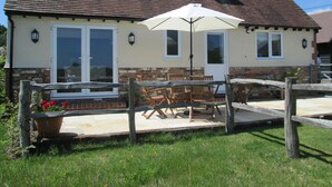 A house with a tiled roof, a front door, and a patio area with a table and chairs.