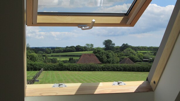 A skylight with a view of a rural landscape, including fields and houses.