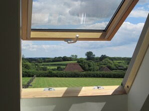 Une lucarne offrant une vue sur un paysage rural, avec des champs et des maisons.