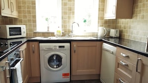 A compact kitchen with a built-in washer and dryer, a microwave, and a sink.