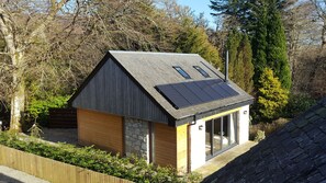 A small, modern cabin with a sloped roof, solar panels, and a stone foundation. - A Perfect Nature Escape- The Trossachs National Park  Callander (Callander)