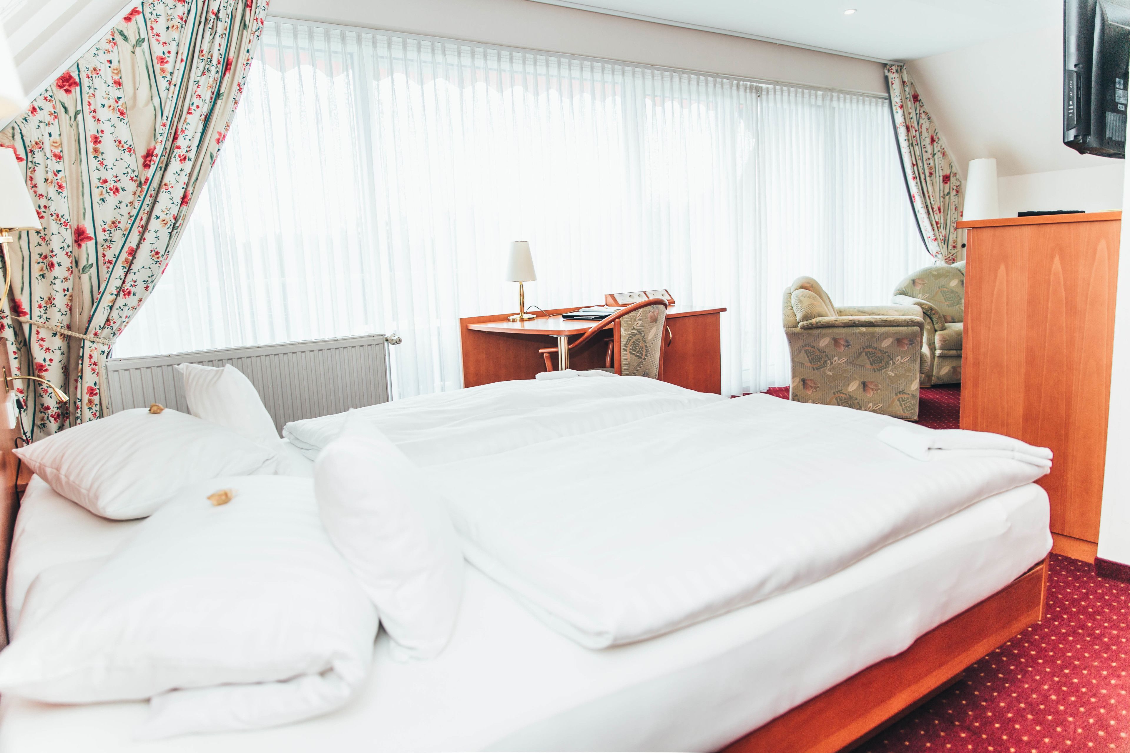 Habitación de hotel con una cama grande, un escritorio, una silla y un televisor.