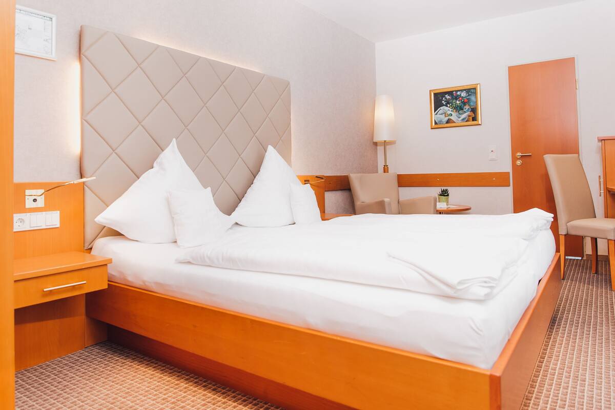 Une chambre d’hôtel avec un grand lit, un bureau, une chaise et une petite table avec une lampe.