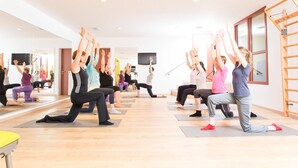 A group of people in a yoga class, seated on mats in a room with wooden floors and mirrors on the walls. - Ringhotel Teutoburger Wald (Tecklenburg)