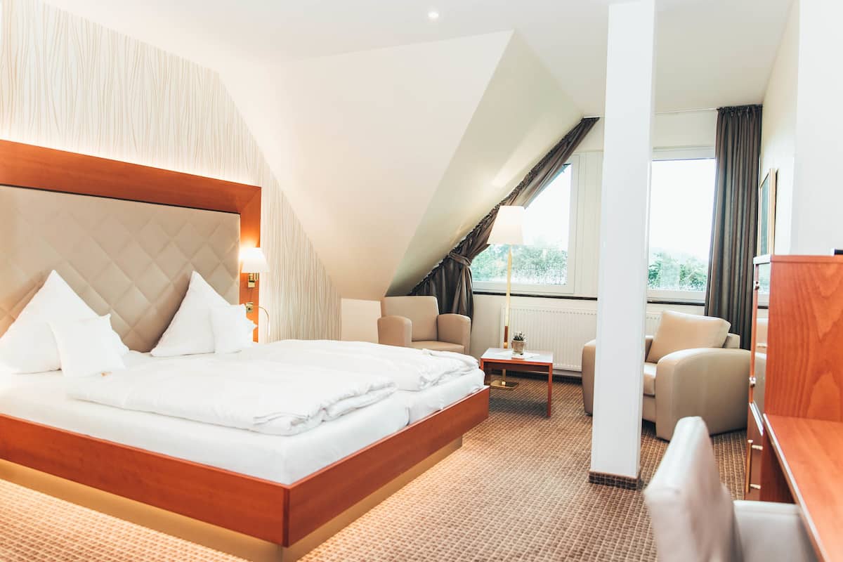 Une chambre d’hôtel moderne, dotée d’un grand lit, d’un canapé, d’un bureau et offrant une vue sur l’extérieur.