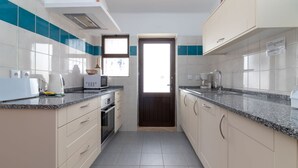Une cuisine moderne avec des armoires blanches, des touches de couleur turquoise, des comptoirs en granit et des appareils électroménagers en acier inoxydable.