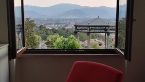 Una sedia rossa in una stanza con un'ampia finestra ad arco che si affaccia su una città e montagne.