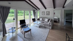 A spacious living room with a large window, a ceiling fan, and a view of the outdoors.