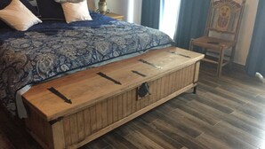 A bedroom with a bed, a wooden chest, and a chair. - Casa Boutique San Miguel Serenata (San Miguel de Allende)