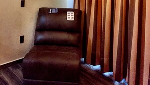 A room with a television mounted on the wall, a brown leather chair, and a curtain with a decorative valance. - Casa Boutique San Miguel Serenata (San Miguel de Allende)
