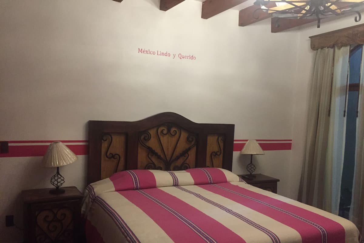 A hotel room with a bed, two bedside tables, and a wall with a decorative border.