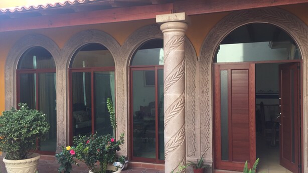A building facade with three arched windows and a central column with leaf carvings. - Casa Boutique San Miguel Serenata (San Miguel de Allende)