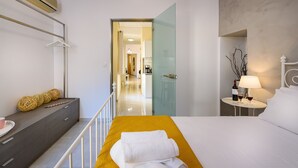 Une chambre d’hôtel moderne, équipée d’un lit, d’une table de chevet et offrant une vue sur le couloir.