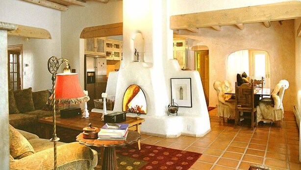 Una sala de estar acogedora con chimenea, vigas de madera y un comedor con sillas.