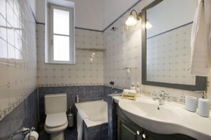A bathroom with a toilet, bathtub, sink, and a calendar on the wall. - Acropolis Neoclassic Mansion: Perfectly situated & fully equipped - Sleeps 6 (Athens)