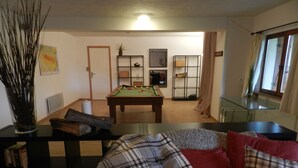 Una sala de estar con mesa de billar, sofá y mesa de centro.