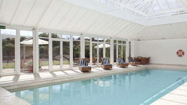 A covered swimming pool with lounge chairs and a glass ceiling. - Bruern Cottages - Aintree (sleeps 6 + 1) (Chipping Norton)
