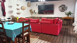 A cozy room with a red sofa, wooden dining table, and a TV mounted on the wall. - CORRALEJO-Villa Tranquila with private pool (La Oliva)