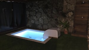 A spa area with a hot tub, stone wall, and potted plant. - CORRALEJO-Villa Tranquila with private pool (La Oliva)
