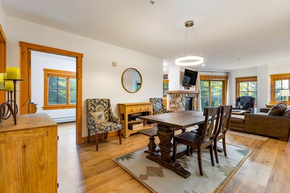 A spacious living room with a wooden dining table, chairs, a sofa, and a TV.