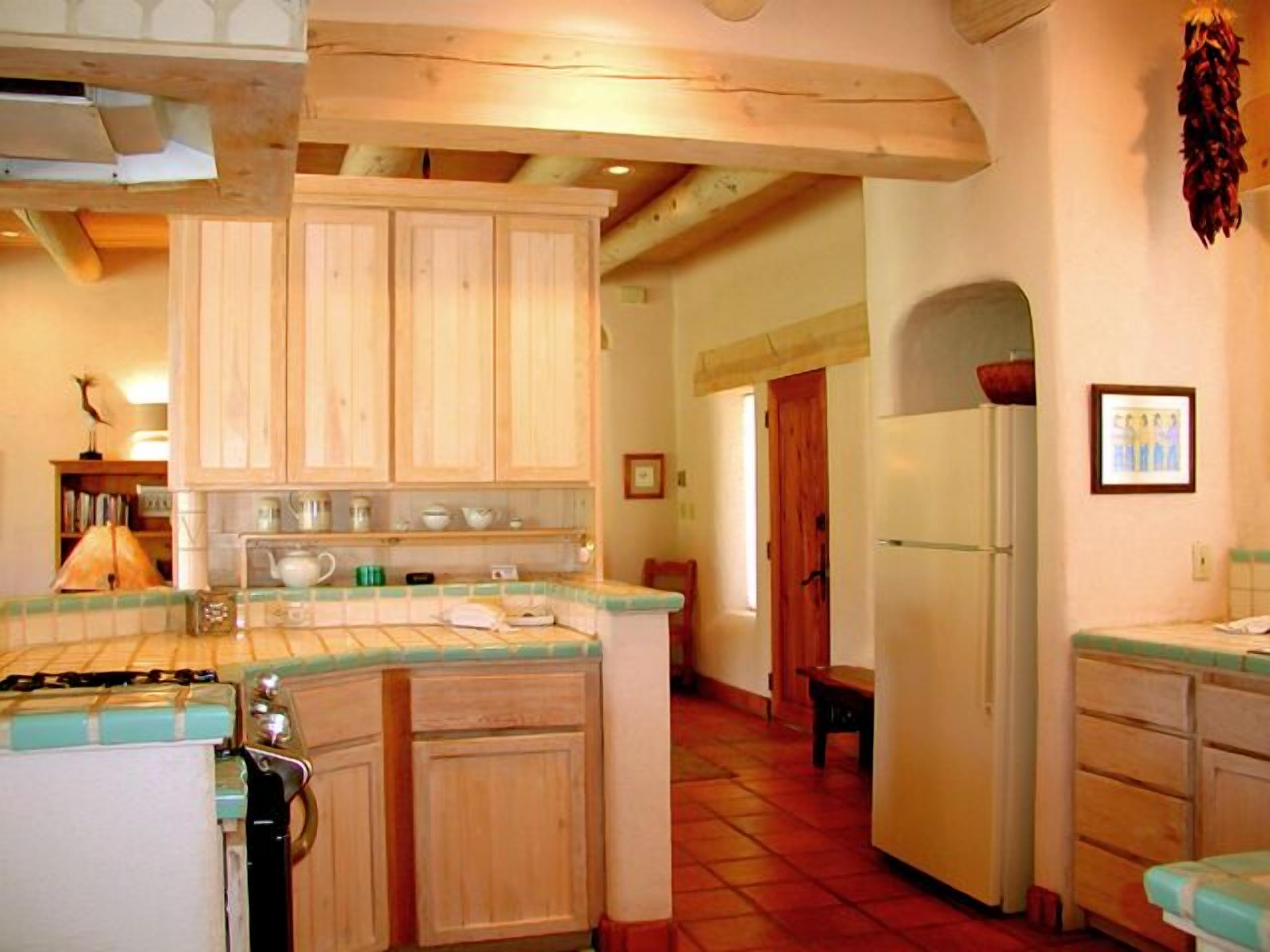 A kitchen with wooden cabinets, a stove, and a refrigerator.