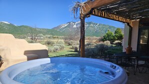 A hot tub with a mountain view, outdoor seating, and a pergola structure.