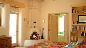 A cozy bedroom with a fireplace, a bookshelf, and a bed with a colorful quilt.