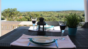 Una mesa dispuesta con platos, cubiertos y vasos, con vistas a un paisaje pintoresco.