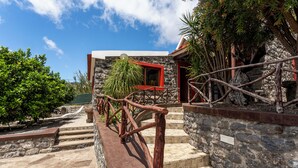 Un edificio de piedra con un ventanal rojo y una escalera de madera que conduce a una puerta.