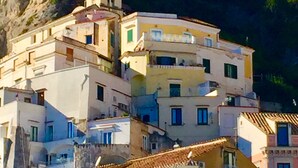 Un bâtiment situé sur la côte, doté de nombreux balcons et d’une tour, et entouré de verdure et d’un paysage rocheux.