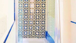 Un espace douche étroit et fermé, avec des carreaux décorés et une porte en verre.