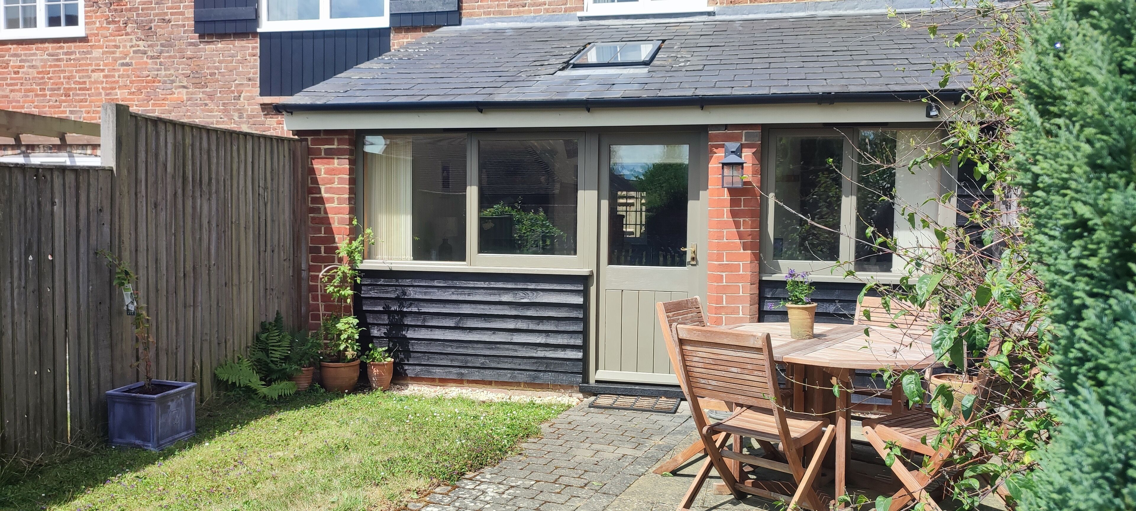 A small brick house with a wooden deck, a window, and a door.