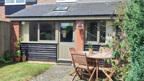 A small brick house with a wooden deck, a window, and a door. - Wheat cottage, Chiddingly, spacious and well equipped character accommodation (chiddingly)