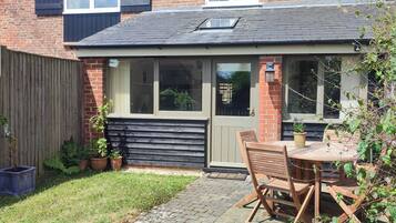 A small brick house with a wooden deck, a window, and a door.