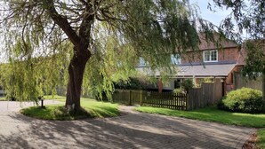 A residential area with a paved driveway leading to a house with a brick facade and a tiled roof. - Wheat cottage, Chiddingly, spacious and well equipped character accommodation (chiddingly)