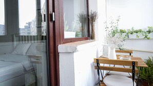 A balcony with a bed, a wooden table, and potted plants. - Diana’s flat No 2  Bucharest - Old  City (Bucharest)