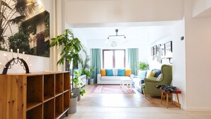 A spacious living room with a wooden bookshelf, a sofa with colorful cushions, a green armchair, and a small table. - Diana’s flat No 2  Bucharest - Old  City (Bucharest)