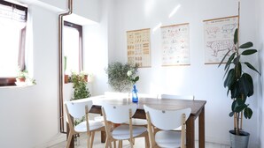A dining area with a wooden table and white chairs, surrounded by potted plants and educational posters on the walls. - Diana’s flat No 2  Bucharest - Old  City (Bucharest)