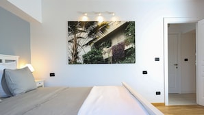 A bedroom with a bed, a nightstand, a wall-mounted picture, and a door leading to another room. - Diana’s flat No 2  Bucharest - Old  City (Bucharest)