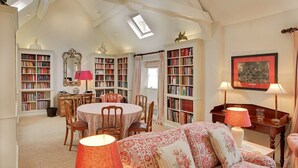 Un salon chaleureux avec une table ronde, des chaises, un canapé et une bibliothèque remplie de livres.
