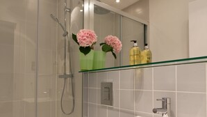 Un baño moderno con ducha acristalada, lavamanos blanco y retrete.
